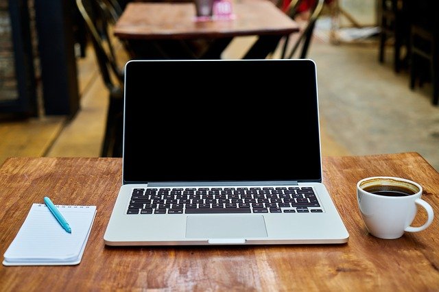 biurko z notesem, laptopem i kawą