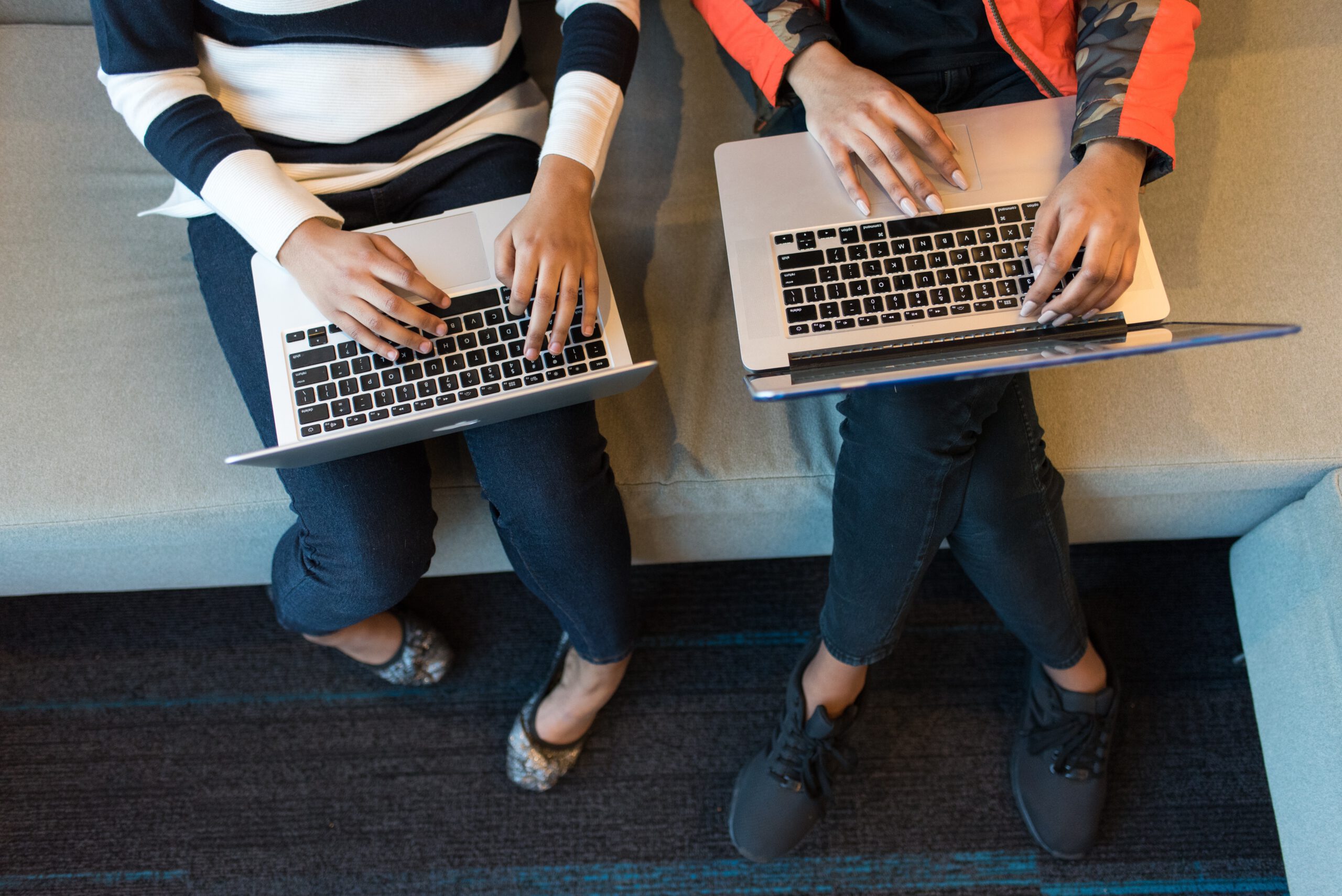 dwie osoby trzymają laptopy na kolanach