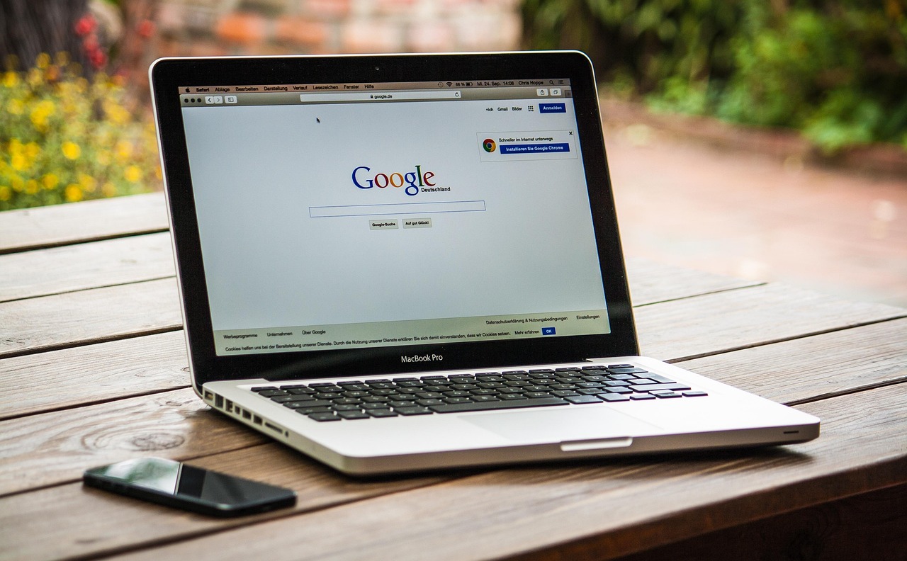 Laptop na drewnianym stole z otwartą wyszukiwarką Google na ekranie